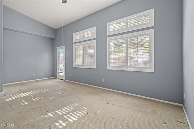 carpeted spare room featuring ceiling fan and vaulted ceiling