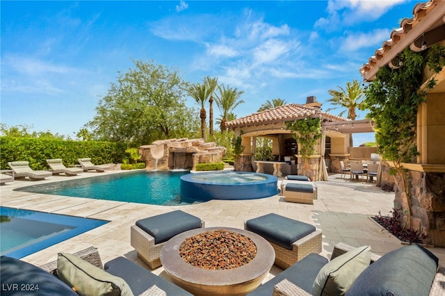 view of swimming pool featuring a patio, an outdoor fire pit, pool water feature, and an in ground hot tub