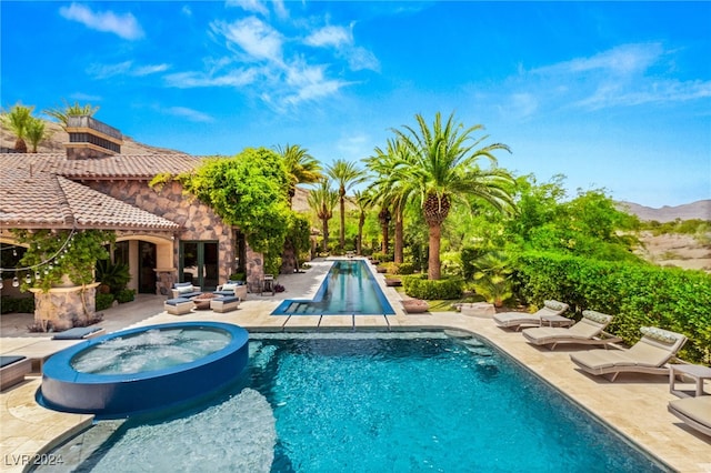 view of swimming pool featuring a patio, a mountain view, and an in ground hot tub