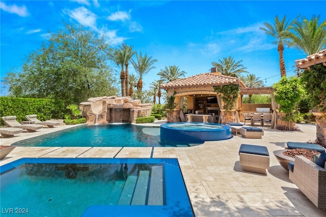 view of swimming pool with an in ground hot tub, a bar, a patio area, pool water feature, and exterior kitchen