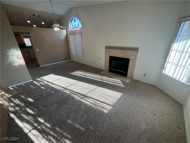 unfurnished living room featuring a fireplace, dark colored carpet, high vaulted ceiling, and ceiling fan