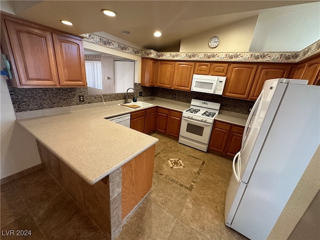 kitchen featuring kitchen peninsula, a kitchen breakfast bar, white appliances, sink, and lofted ceiling