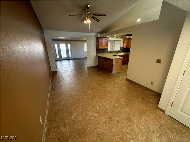 kitchen featuring a textured ceiling, ceiling fan, sink, and vaulted ceiling