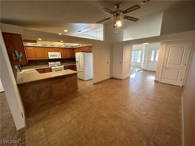 kitchen featuring kitchen peninsula, a textured ceiling, white appliances, and sink