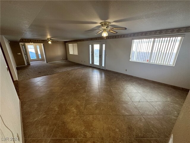 carpeted spare room with a textured ceiling, a wealth of natural light, and ceiling fan