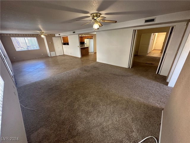 unfurnished living room featuring ceiling fan, carpet, and a textured ceiling