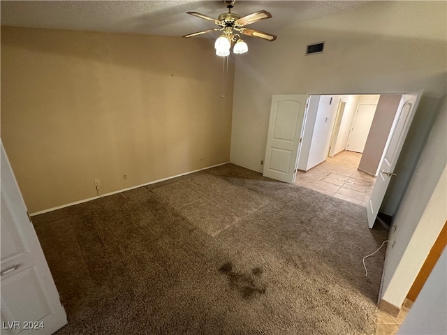 carpeted empty room with lofted ceiling, ceiling fan, and a textured ceiling