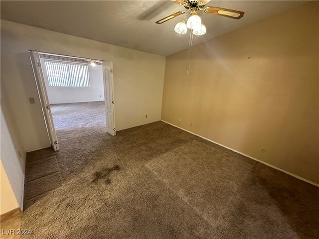 spare room featuring ceiling fan and dark colored carpet