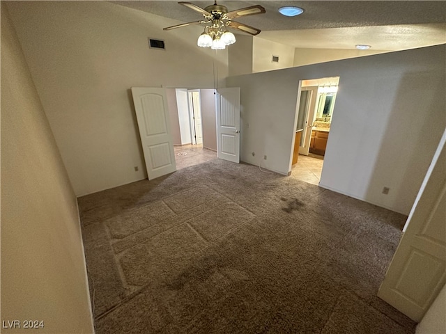 interior space featuring lofted ceiling, light carpet, ceiling fan, and a textured ceiling