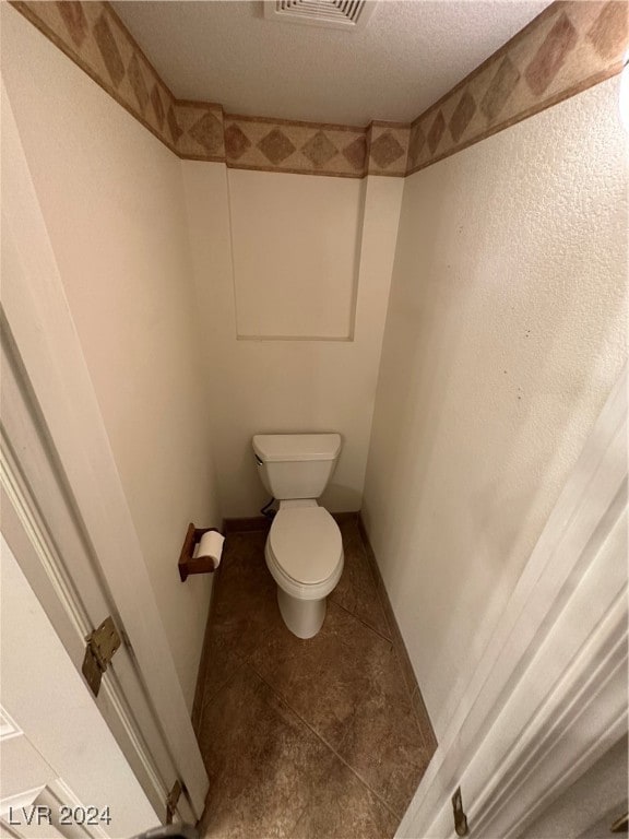 bathroom with tile patterned floors, a textured ceiling, and toilet