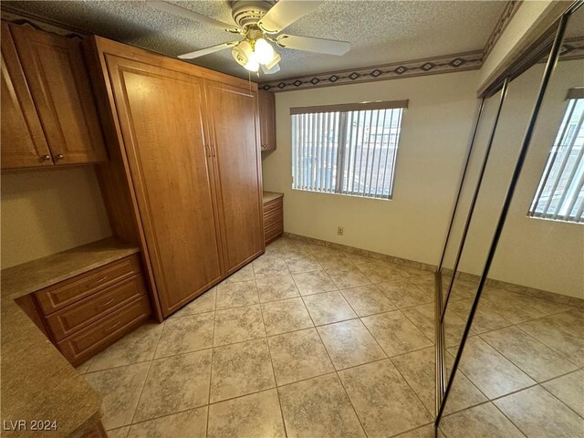 3218 Ocotillo Dr, Laughlin, NV 89029 - unfurnished bedroom with multiple windows, a textured ceiling, light tile patterned floors, ceiling fan, and baseboards