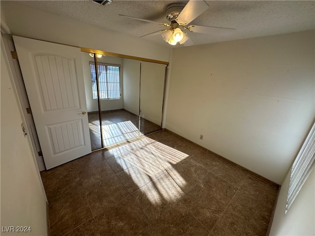 unfurnished bedroom with ceiling fan, a closet, and a textured ceiling