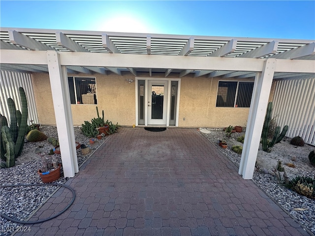 view of exterior entry featuring a pergola and a patio area