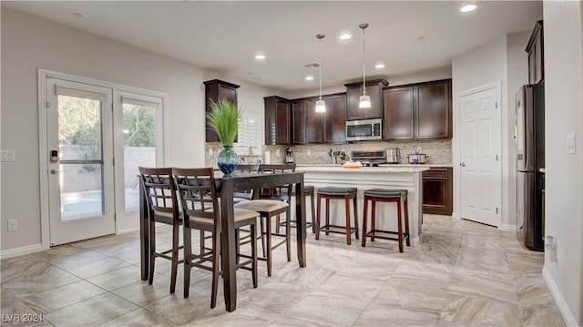 kitchen with dark brown cabinetry, tasteful backsplash, hanging light fixtures, a kitchen breakfast bar, and stainless steel appliances