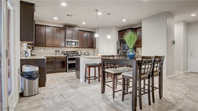 kitchen featuring dark brown cabinetry, decorative light fixtures, stainless steel appliances, and decorative backsplash