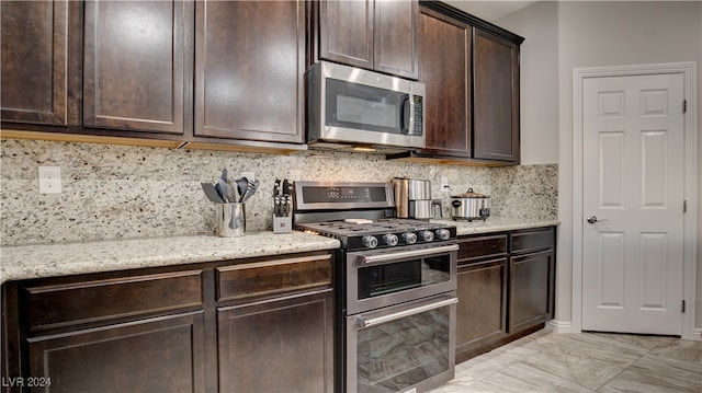 kitchen with light stone counters, decorative backsplash, appliances with stainless steel finishes, and dark brown cabinets