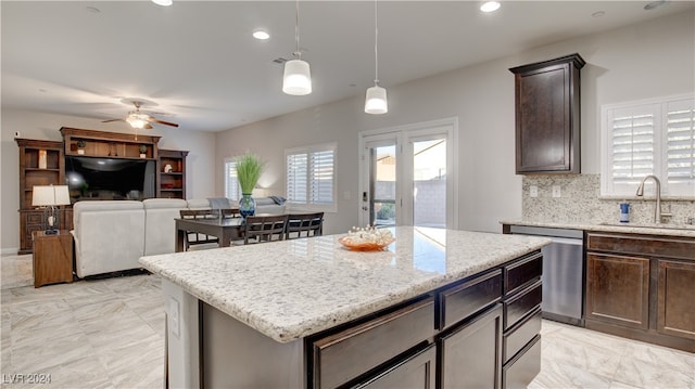 kitchen with pendant lighting, tasteful backsplash, sink, a center island, and dark brown cabinets