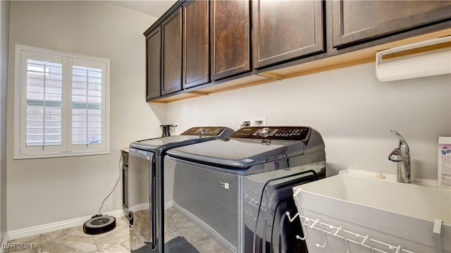 clothes washing area featuring cabinets, sink, and washer and dryer