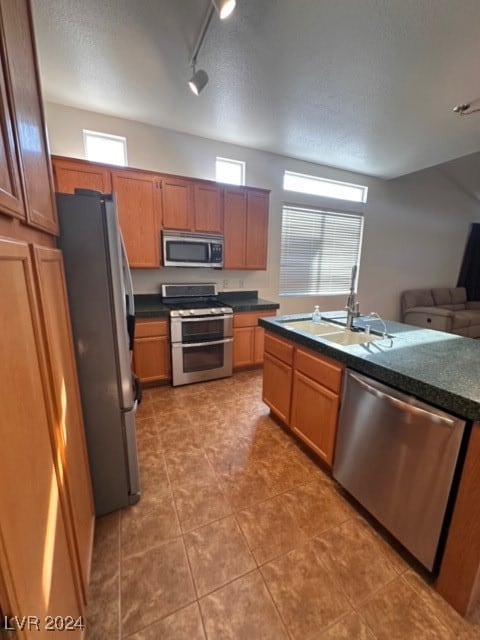 kitchen featuring sink, rail lighting, tile patterned floors, a textured ceiling, and appliances with stainless steel finishes