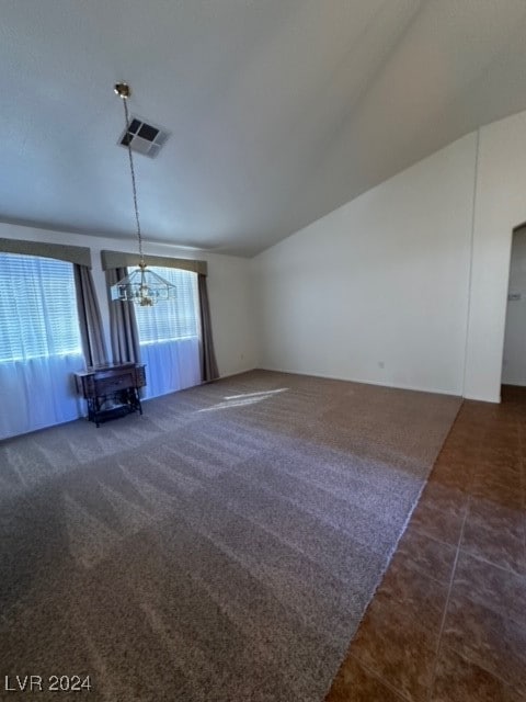 unfurnished living room with a chandelier, vaulted ceiling, and dark colored carpet