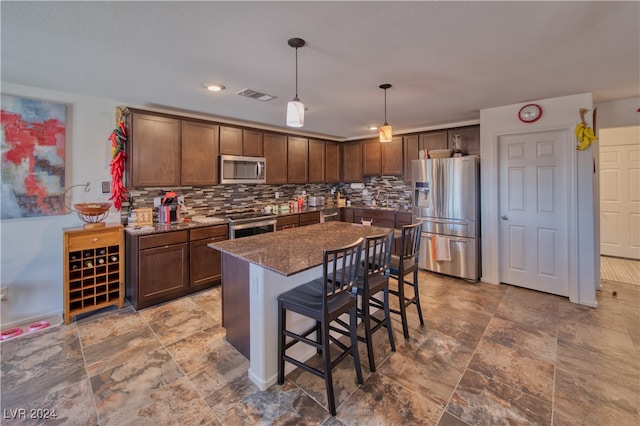 kitchen featuring a kitchen bar, a center island, hanging light fixtures, backsplash, and appliances with stainless steel finishes