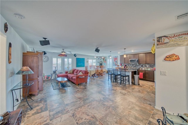 living room with a ceiling fan, visible vents, and baseboards