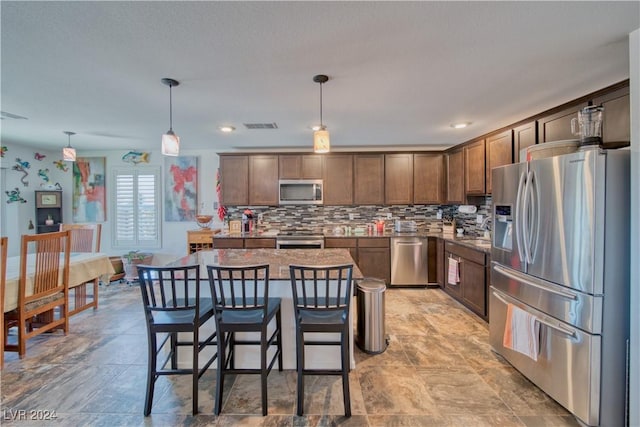 kitchen with stainless steel appliances, visible vents, backsplash, a center island, and pendant lighting