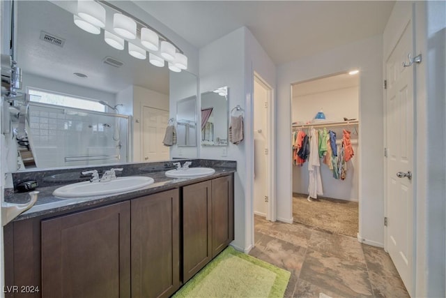 bathroom featuring a stall shower, a walk in closet, visible vents, and a sink