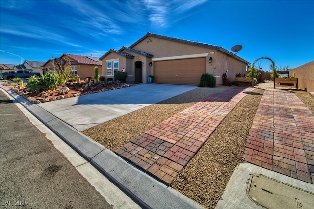 mediterranean / spanish-style home featuring concrete driveway, a tiled roof, an attached garage, and stucco siding