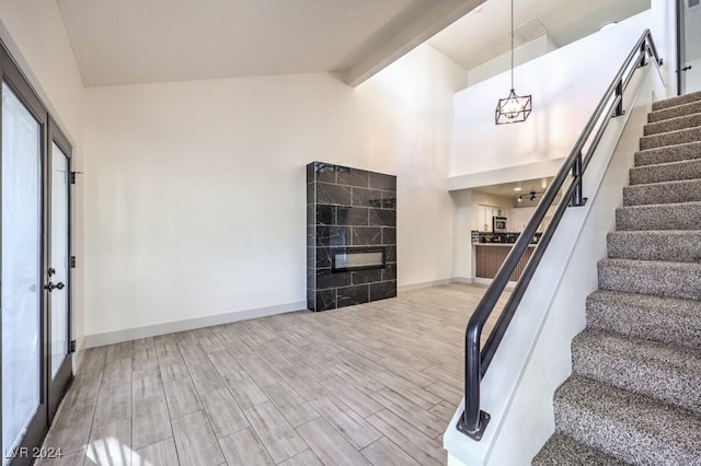 interior space featuring beamed ceiling, high vaulted ceiling, a chandelier, wood-type flooring, and a fireplace