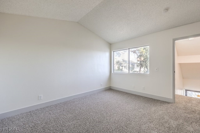 carpeted empty room with a textured ceiling and vaulted ceiling