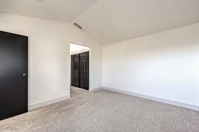 carpeted spare room with lofted ceiling