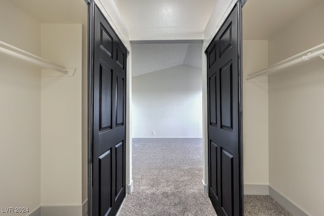 corridor with carpet and vaulted ceiling