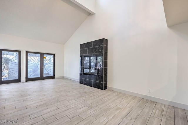 unfurnished living room featuring french doors, light hardwood / wood-style floors, and high vaulted ceiling