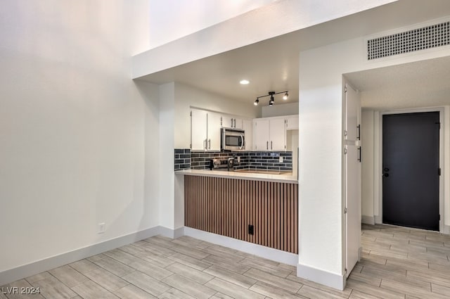 kitchen with white cabinets, light wood-type flooring, and tasteful backsplash