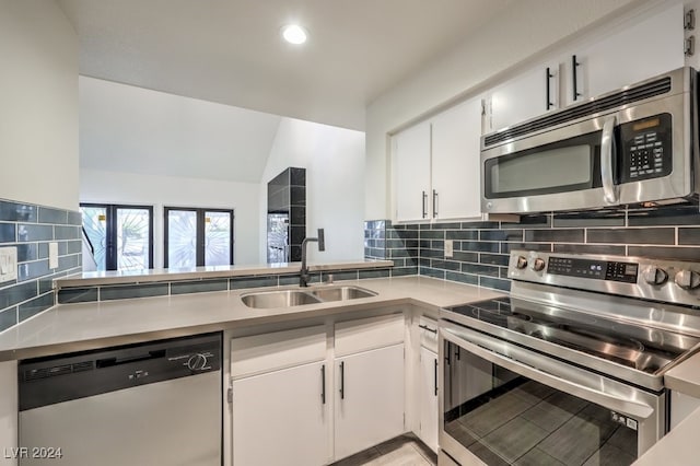 kitchen featuring decorative backsplash, stainless steel appliances, sink, white cabinets, and lofted ceiling