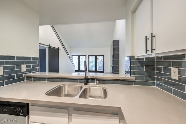 kitchen featuring a barn door, white cabinetry, sink, and dishwashing machine