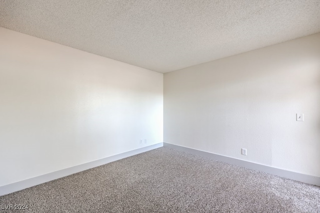 carpeted empty room featuring a textured ceiling