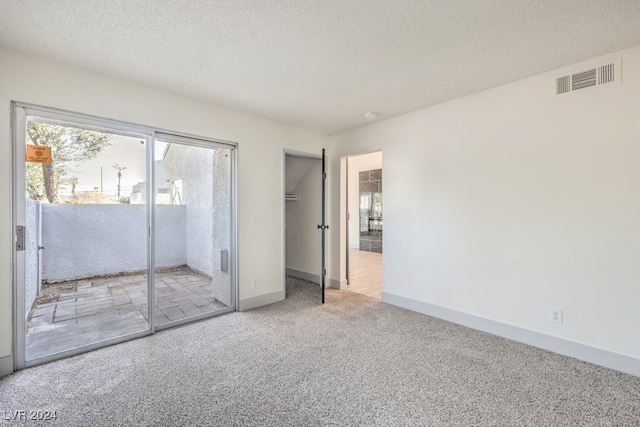 unfurnished bedroom with access to exterior, a textured ceiling, carpet floors, and a closet