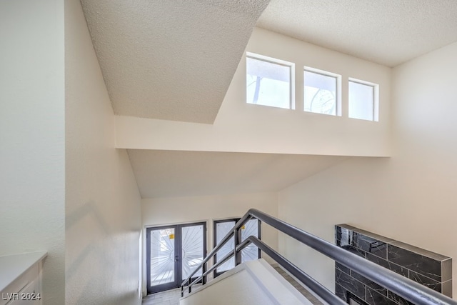 staircase featuring a textured ceiling and vaulted ceiling