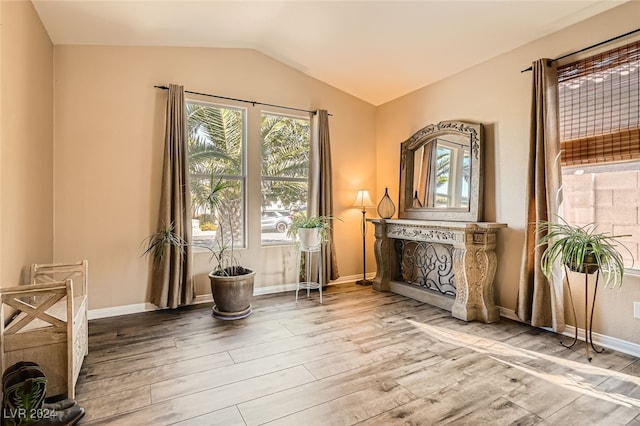 unfurnished room with hardwood / wood-style floors, lofted ceiling, and a fireplace