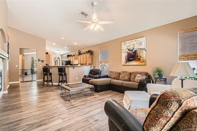 living room featuring ceiling fan, lofted ceiling, and light hardwood / wood-style flooring