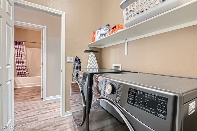 washroom with washing machine and clothes dryer and light wood-type flooring