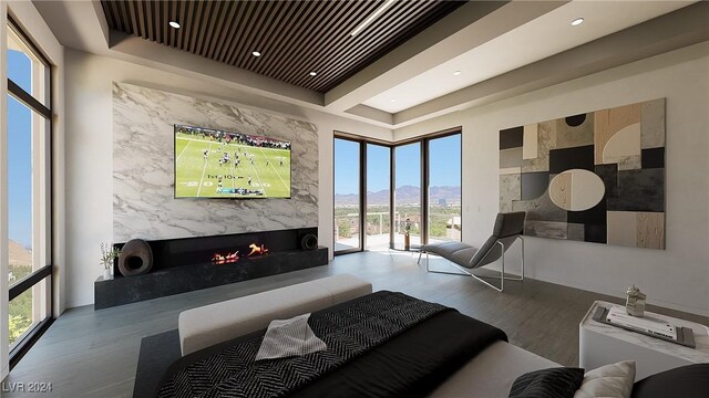 bedroom with a fireplace, multiple windows, a mountain view, and light hardwood / wood-style flooring