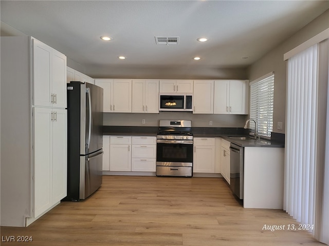 kitchen featuring white cabinets, stainless steel appliances, and light hardwood / wood-style flooring