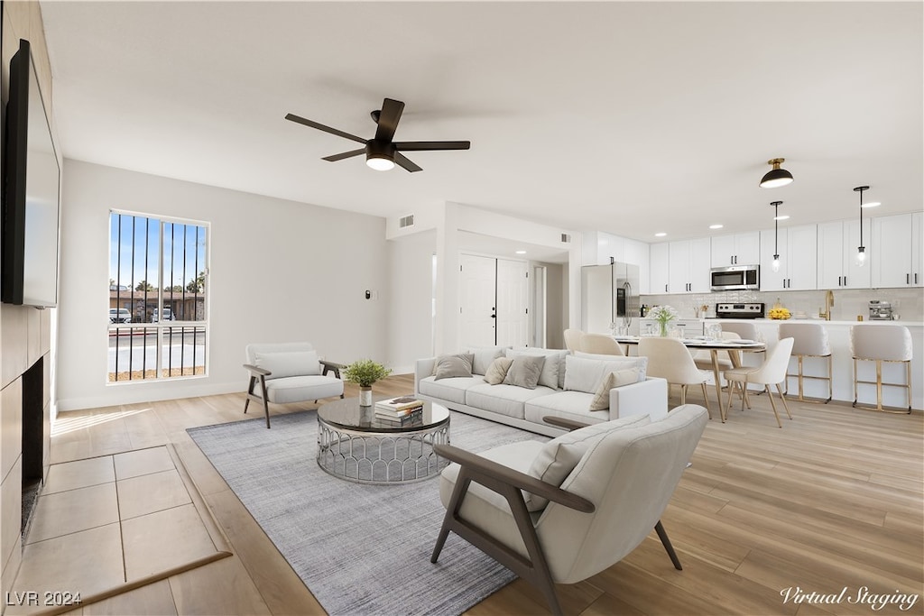 living room featuring ceiling fan and light hardwood / wood-style floors