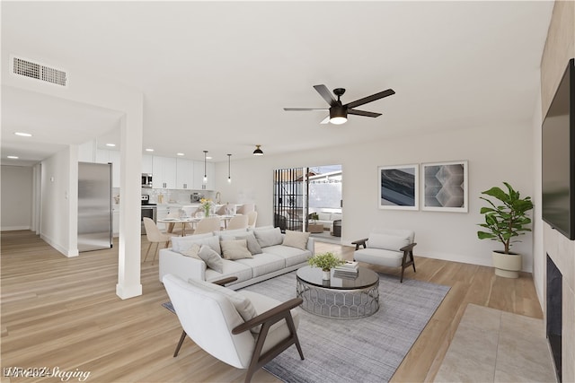 living room featuring ceiling fan and light hardwood / wood-style flooring