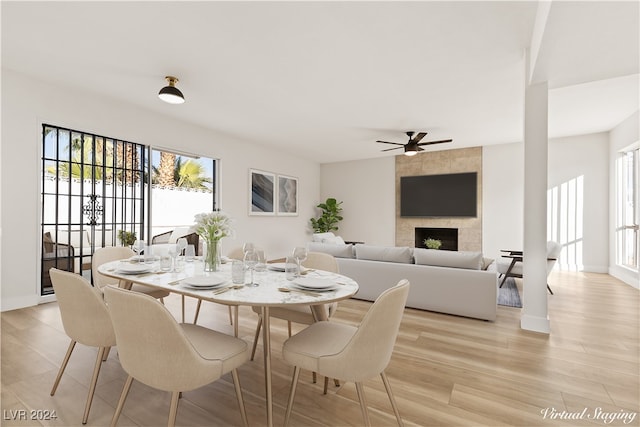 dining area with ceiling fan, a fireplace, and light wood-type flooring