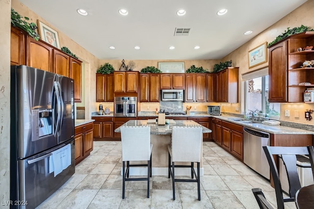 kitchen featuring a breakfast bar, appliances with stainless steel finishes, a kitchen island, and sink