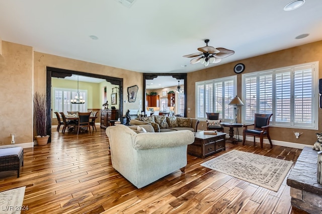 living room featuring ceiling fan with notable chandelier, hardwood / wood-style flooring, and plenty of natural light